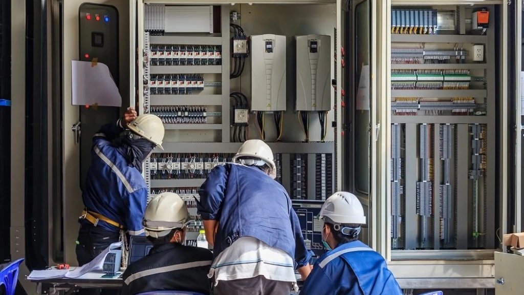 Técnicos con casco trabajando en un tablero eléctrico