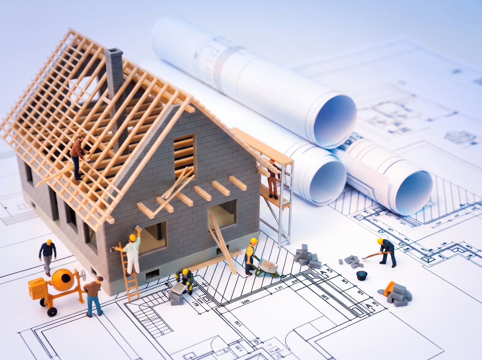 Maqueta de una vivienda en construcción con obreros en miniatura sobre planos