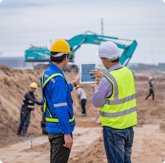 Supervisor con tablet junto a una excavadora en obra