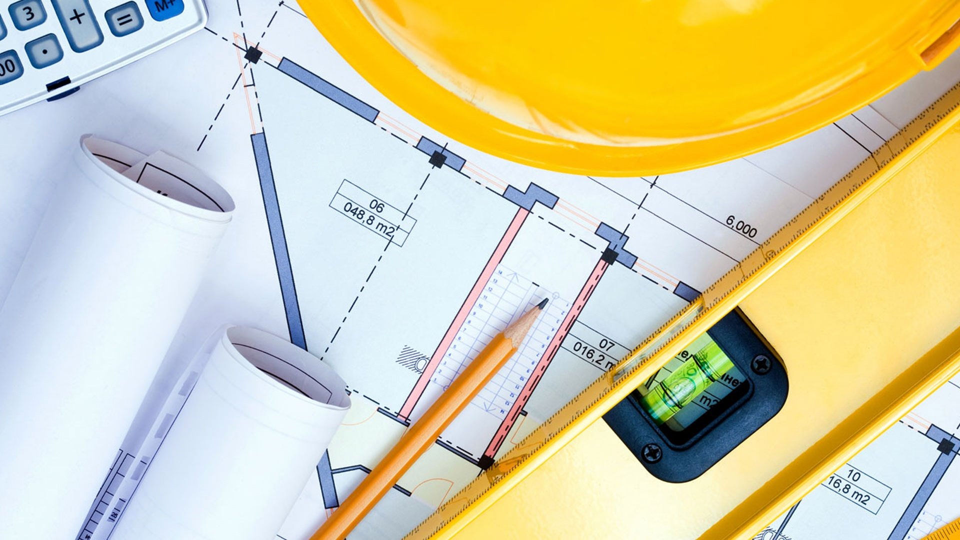 Planos de ingeniería con nivel y casco de seguridad